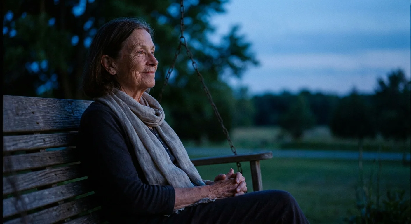 A peaceful portrait of an older woman sitting on a porch at twilight, looking reflective.